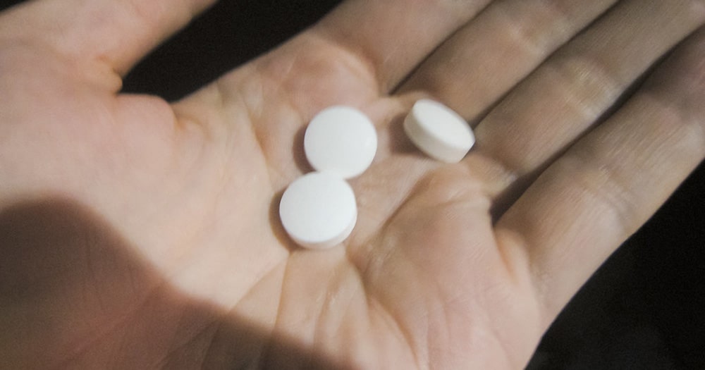 Hand holding three pills